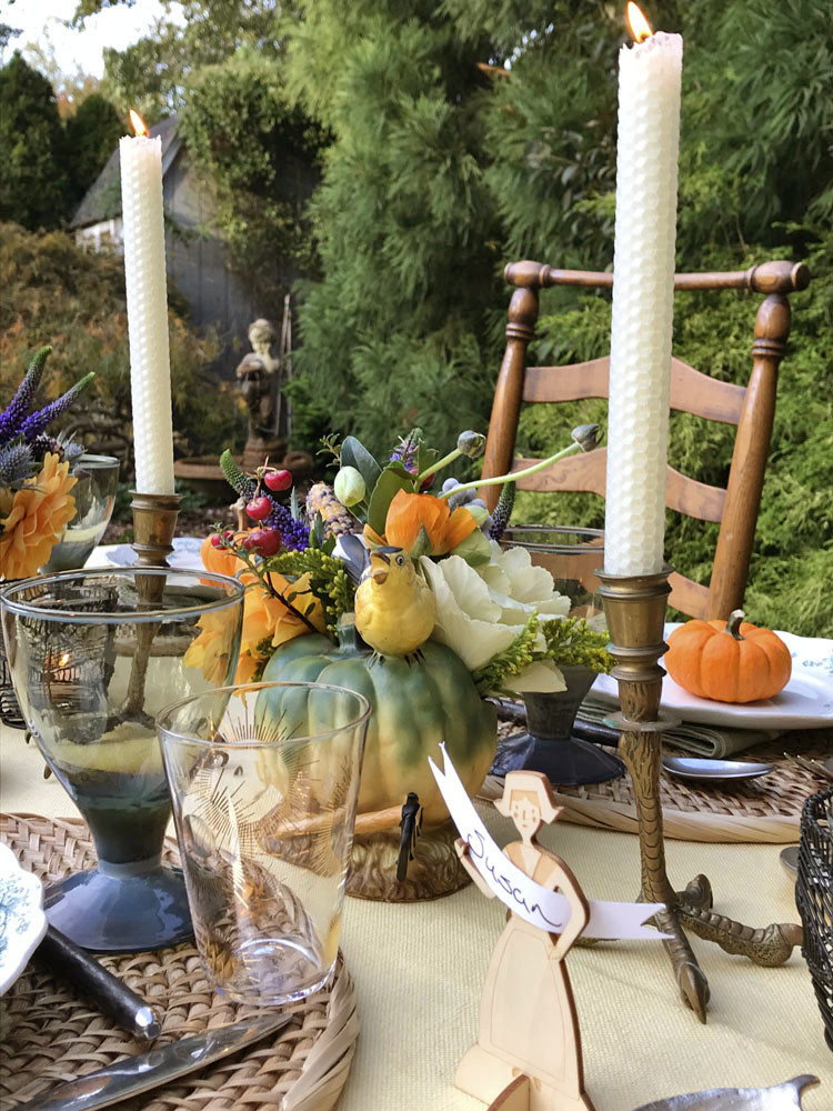 A sweet little bird perches on a ceramic squash flanked by a pair antique clawfoot candlesticks.